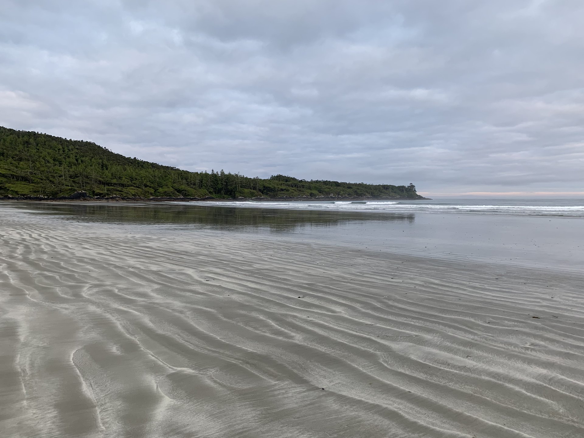 Revelation 5 NASB.  Flat, wavy sand along the ocean coastline on an overcast day.